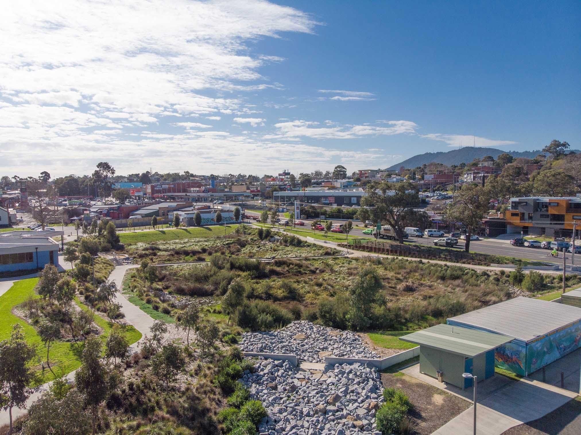 Aerial view over Boronia's landscaped creek reserve, with the shopping strip and the hills behind